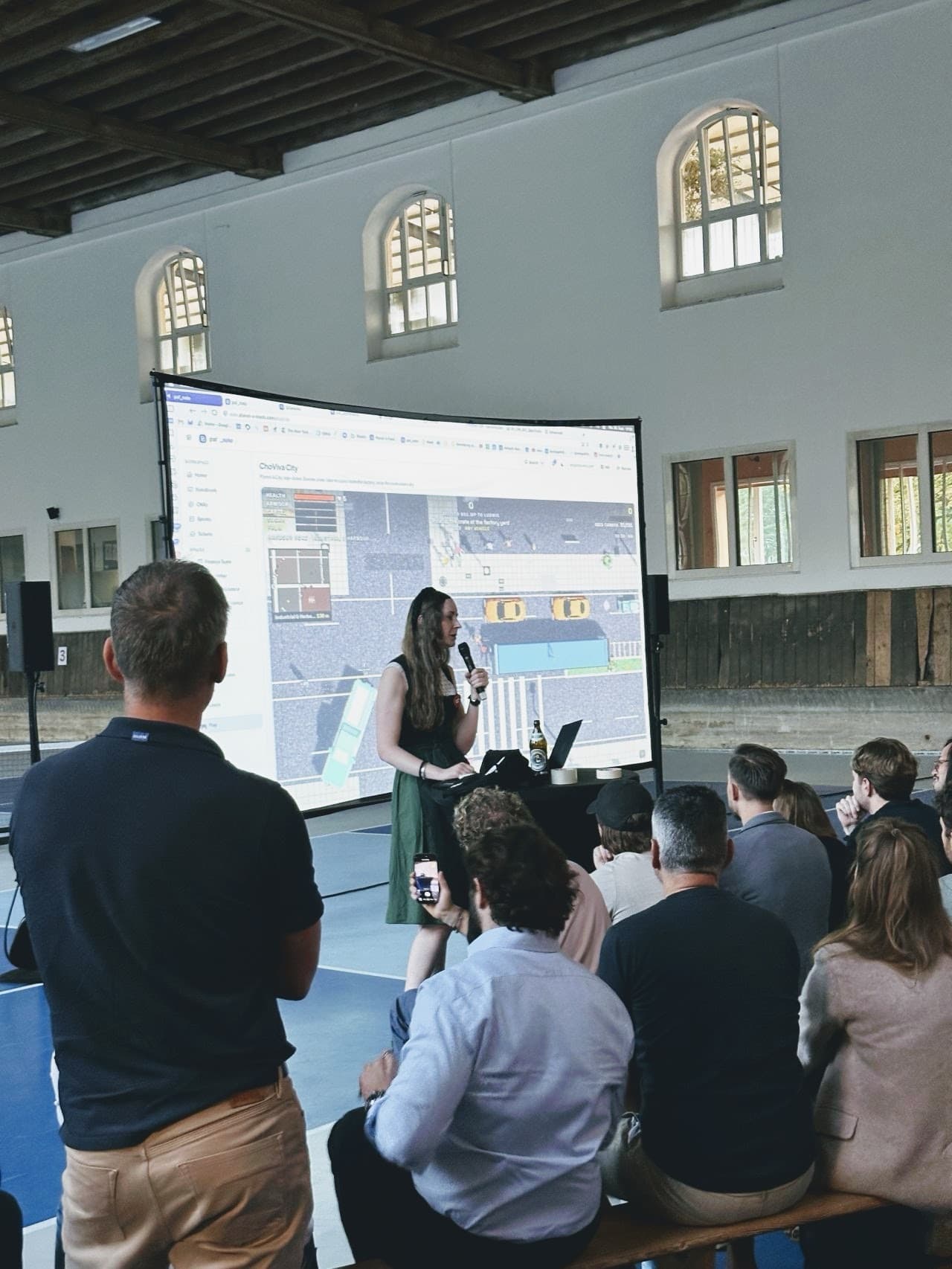 Speaker presenting a live game demo while the audience films it