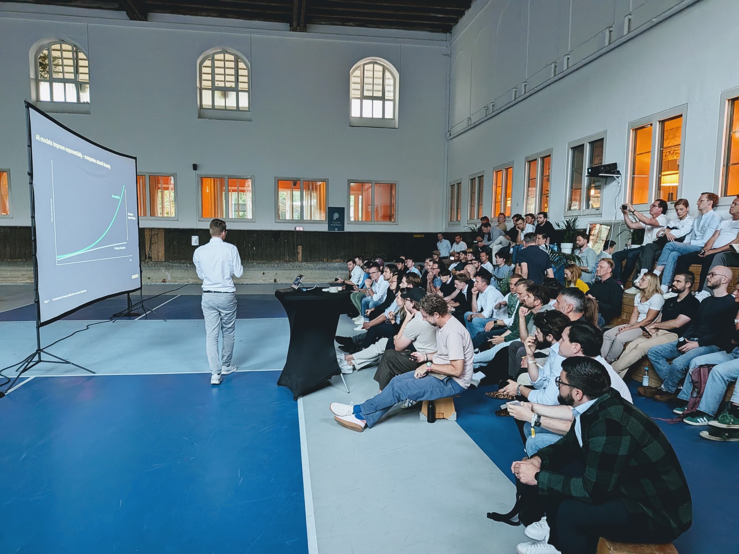 Siemens speaker presenting the “AI models improve exponentially” chart to a full room